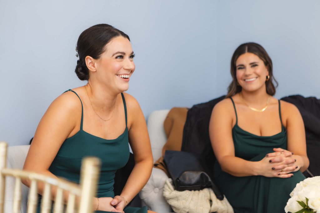 Two bridesmaids candidly laughing during wedding preparation.