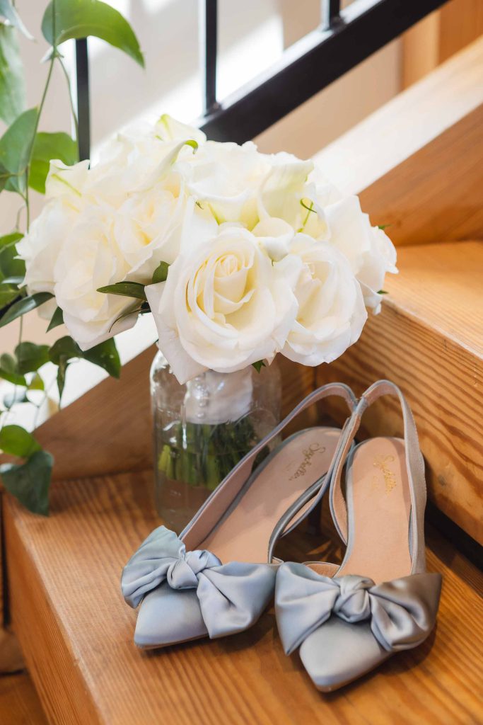 A pair of wedding shoes and a vase of flowers on a staircase.
