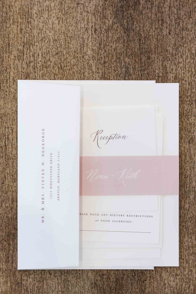 A detailed wedding invitation on a wooden table.