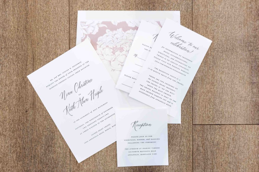 A set of wedding invitations with intricate details on a wooden floor.