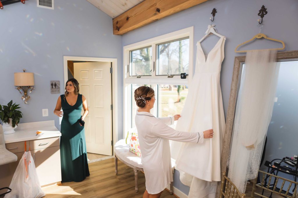 A bride is candidly preparing in a room with a mirror for her wedding.