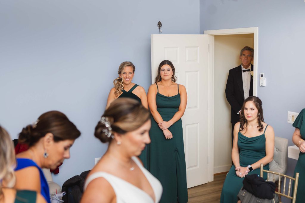 On the day of the wedding, the bride and her bridesmaids pose candidly in the doorway while preparing for the ceremony.