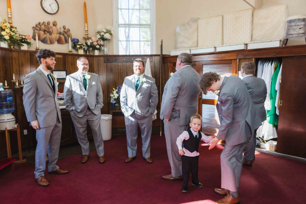 Groom and groomsmen prepare for wedding with a little boy.
