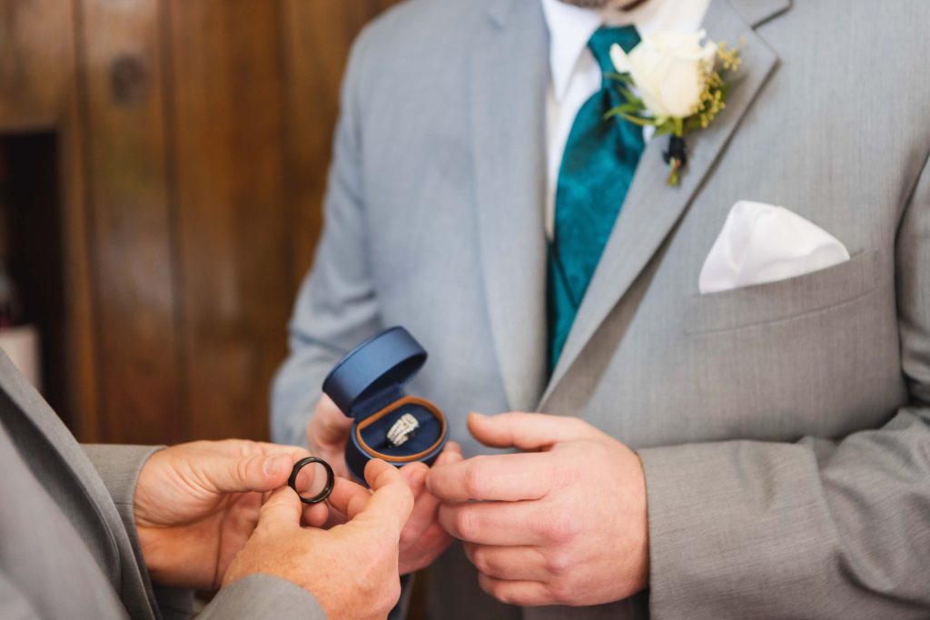 A man is putting a ring on a man's finger during a wedding ceremony.