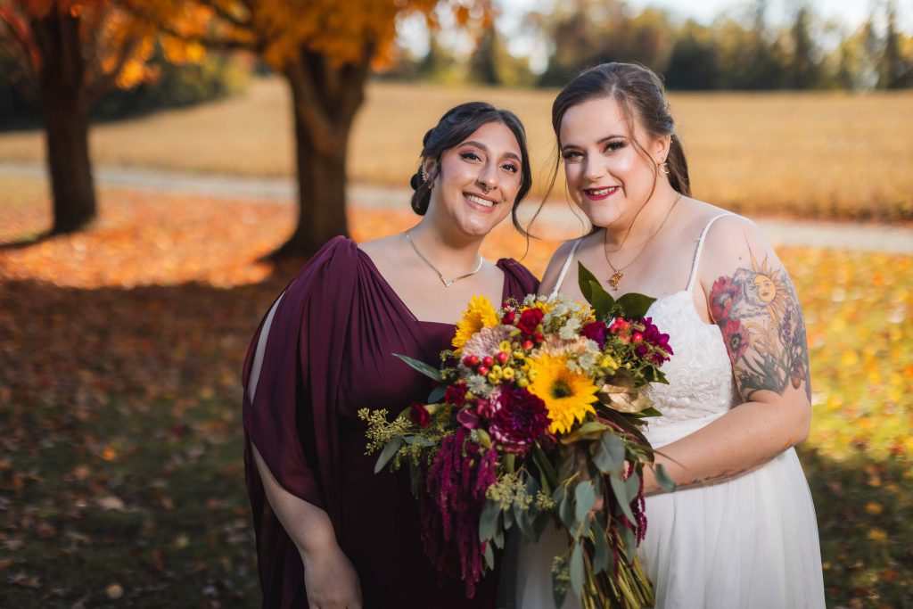 Two brides posing for a wedding portrait in the fall.
