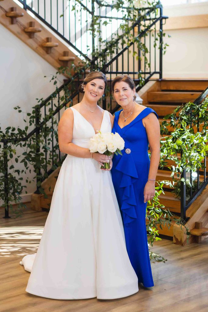 Two brides posing for a wedding portrait in front of a staircase.