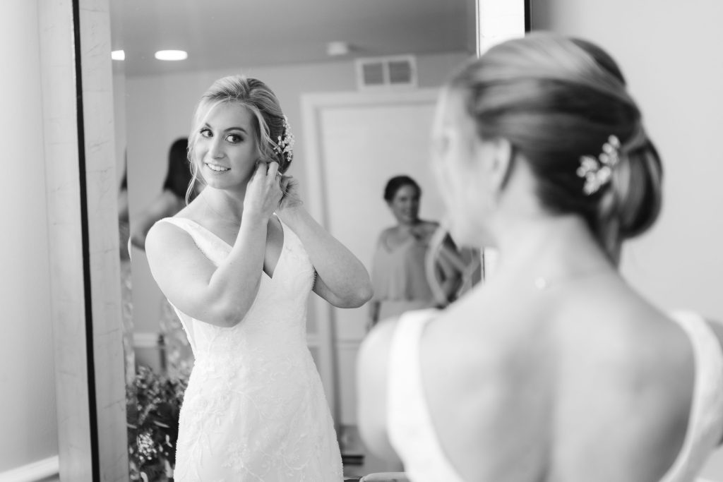A candid bride preparing for her wedding in front of a mirror.