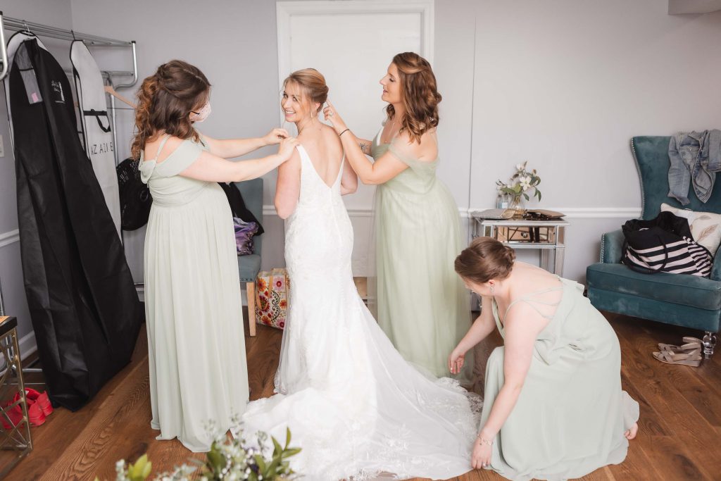 A candid wedding preparation scene of a bride and her bridesmaids in a room.