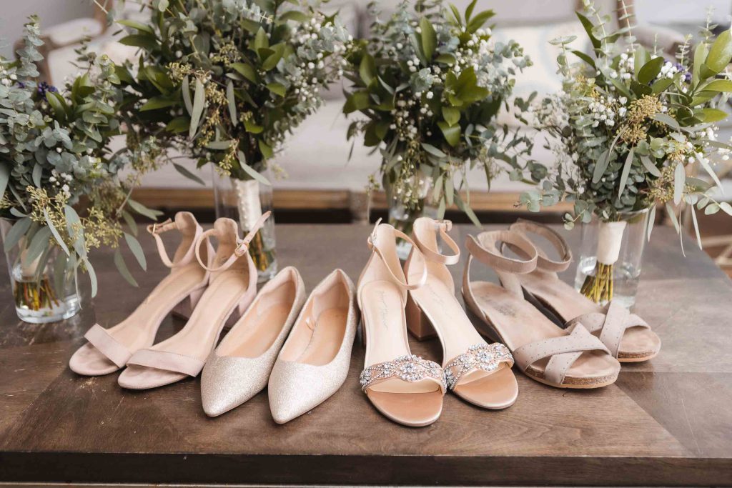 Details of bridesmaids' shoes and bouquets on a wedding table.