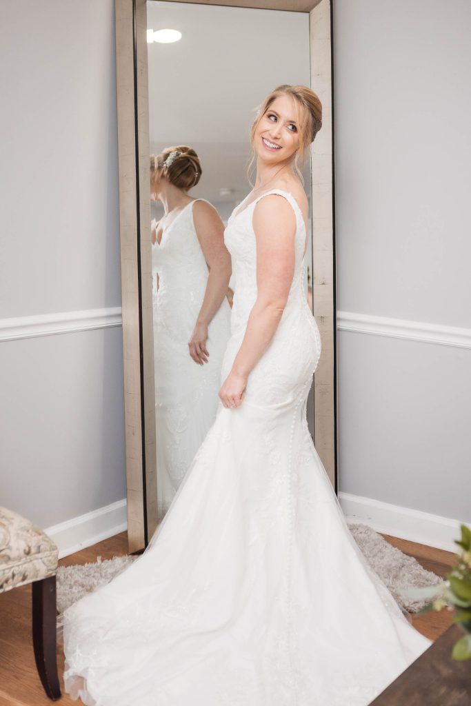 A candid bride preparing for her wedding in front of a mirror.