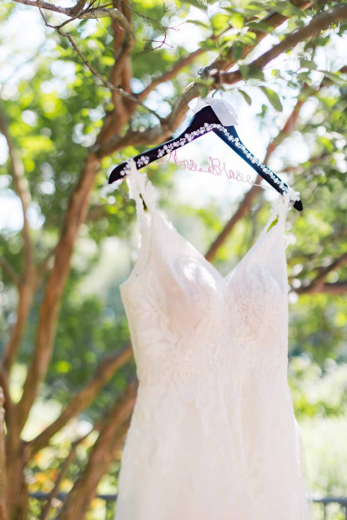 A detailed wedding dress hanging in a park.