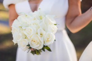 A bride is holding a bouquet of white flowers at her wedding.