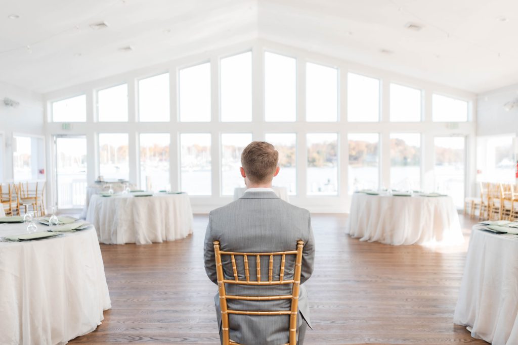 A candid man sitting in a chair at a wedding reception.