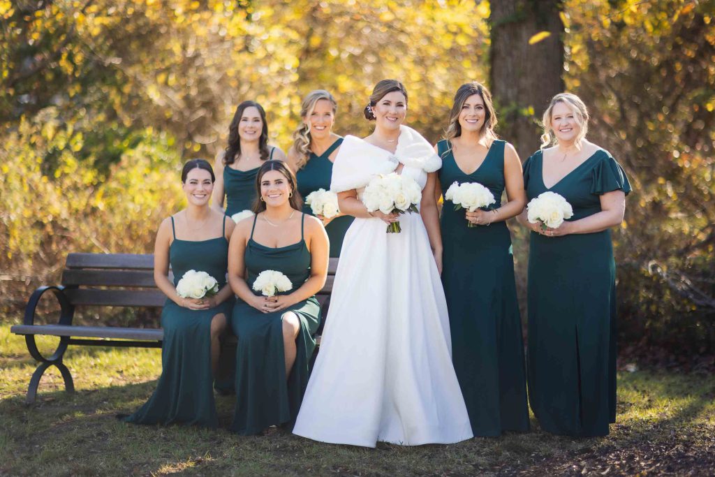 Bridesmaids in emerald dresses posing for a wedding portrait.