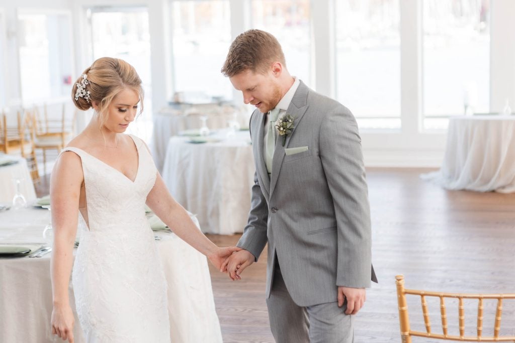 A candid bride and groom holding hands during wedding preparations.