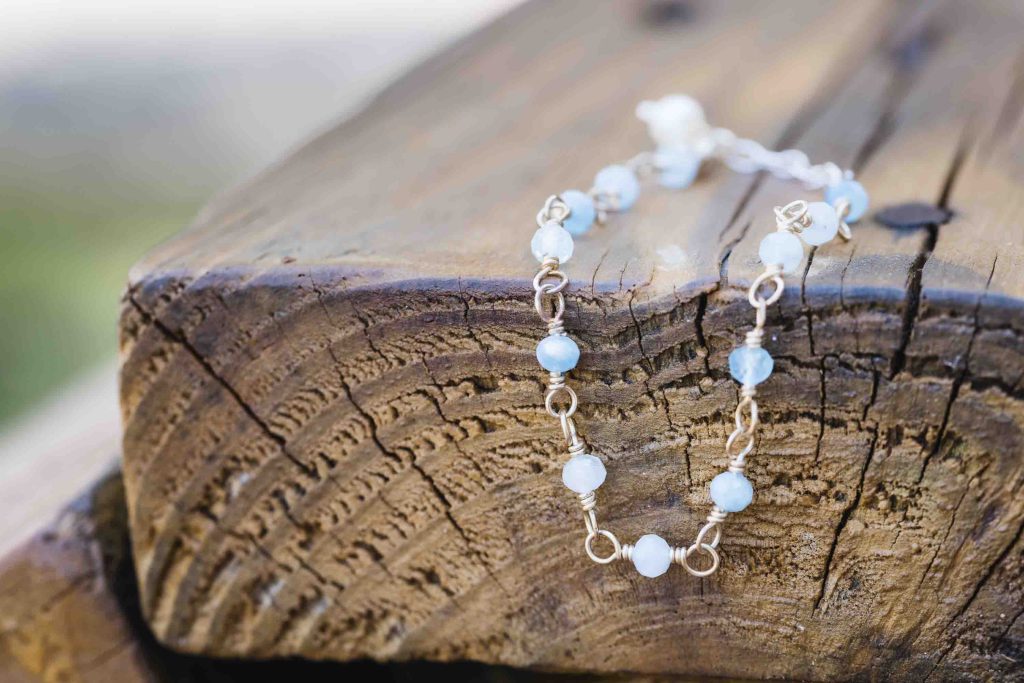 A wedding bracelet with blue and white beads on top of a piece of wood.