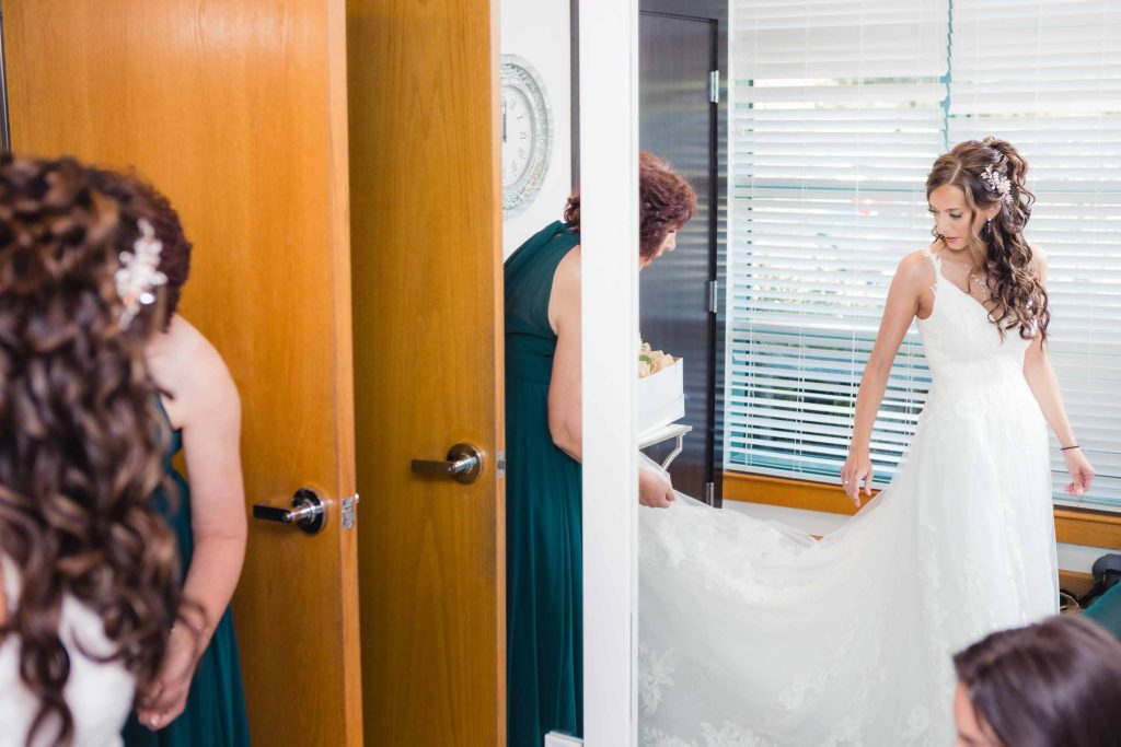 A candid bride preparing for her wedding in her wedding dress.