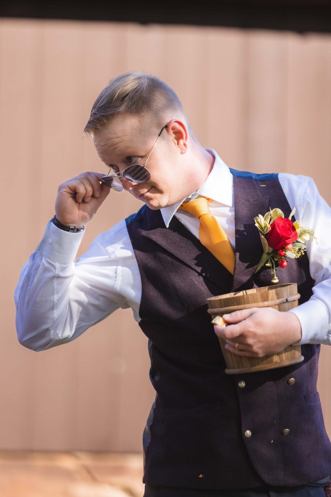 A man in a vest holding flowers at a wedding ceremony.