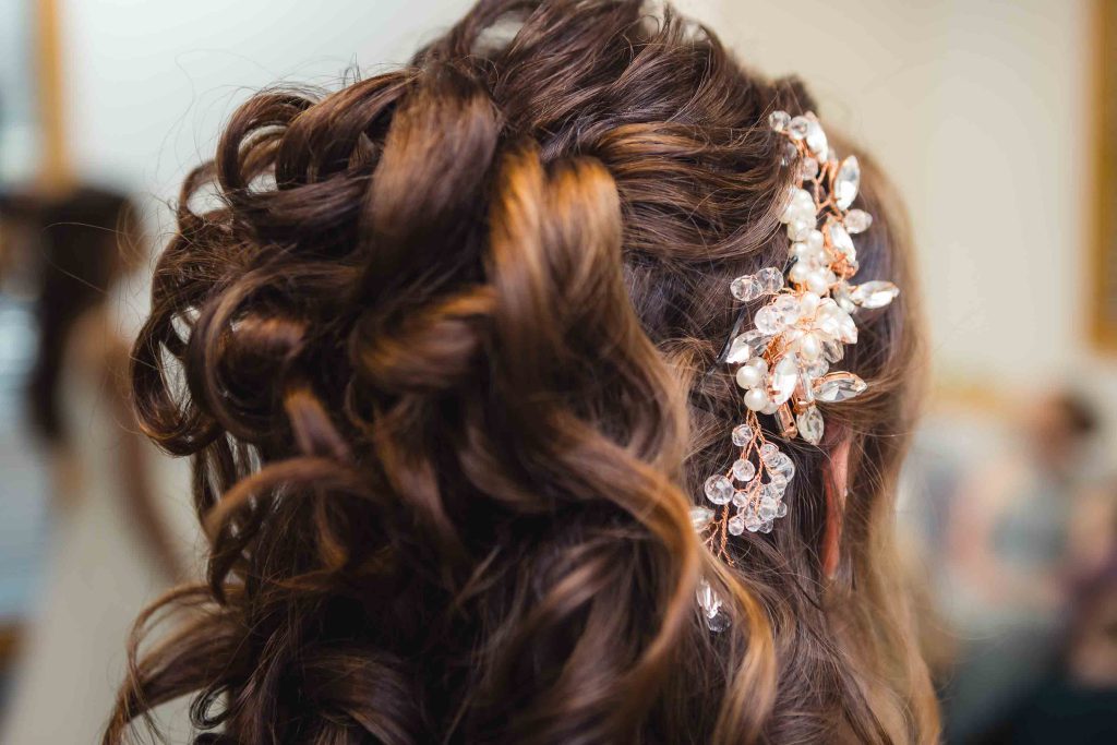 The bride's wedding hairstyle showcases intricate details and a flower headpiece.