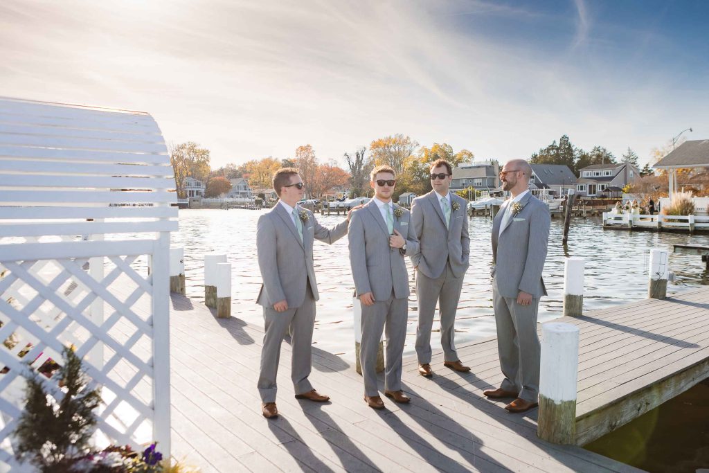 A wedding portrait of groomsmen standing on a dock.
