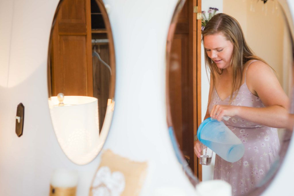 A woman candidly pouring water into a glass in preparation for a wedding.