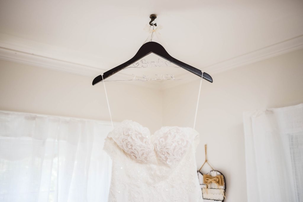 A detailed wedding dress hanging in a room.