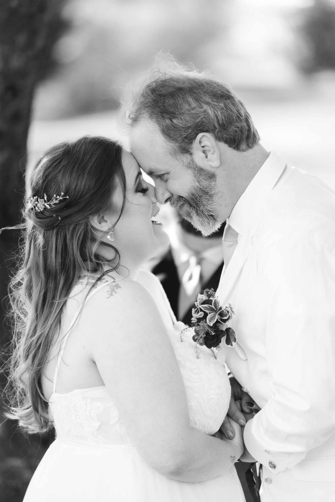 A black and white photo capturing the intimate wedding ceremony as the bride and groom share a kiss.