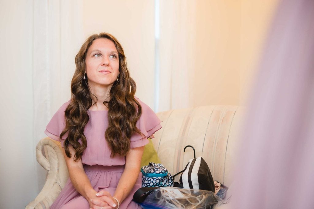 A woman in a pink dress candidly sitting on a couch.