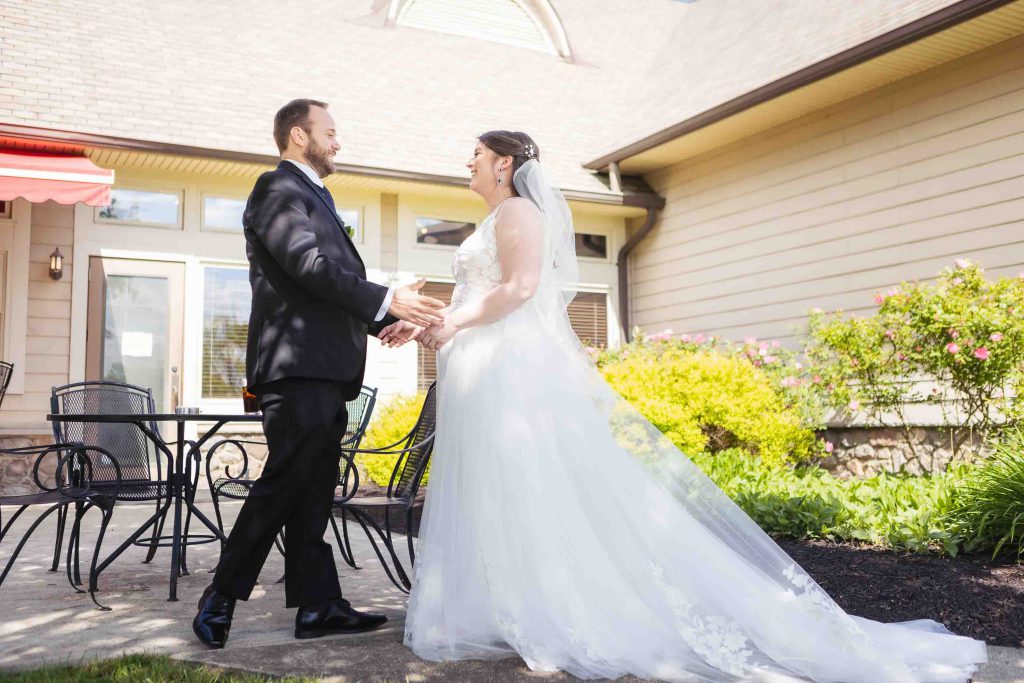 A candid wedding preparation moment with a bride and groom in front of a house.