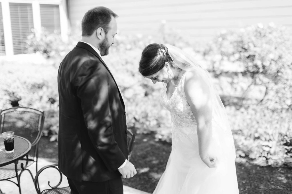 A candid black and white photo capturing the wedding preparation of a bride and groom.