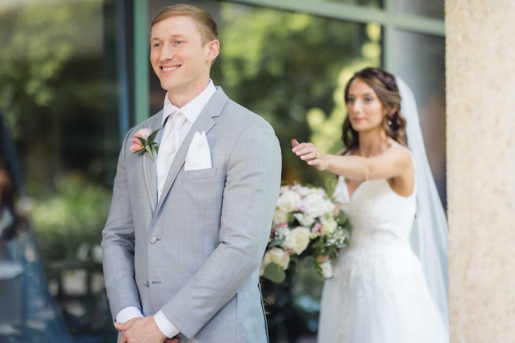 A candid bride and groom standing in front of a building on their wedding day.