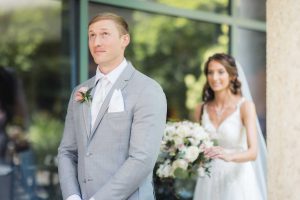 A candid wedding couple standing in front of a glass door.