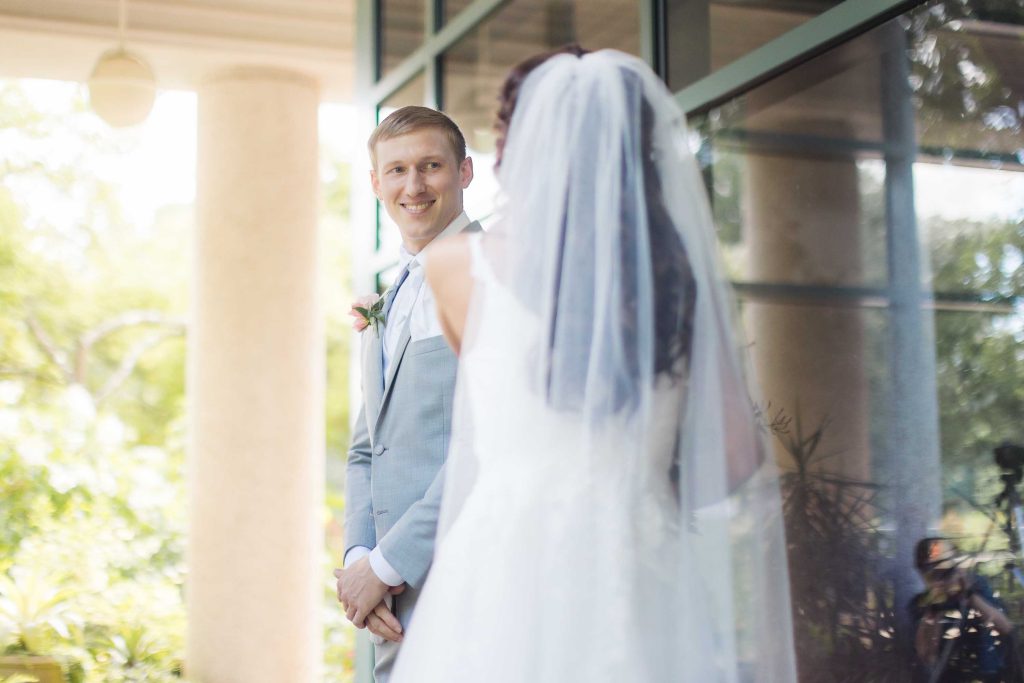 A candid wedding moment, with the bride and groom looking at each other in front of a building.