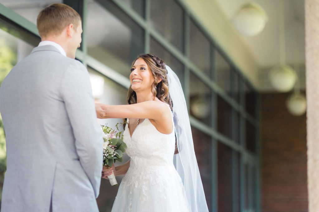 A candid bride and groom smiling at each other during their wedding preparation.