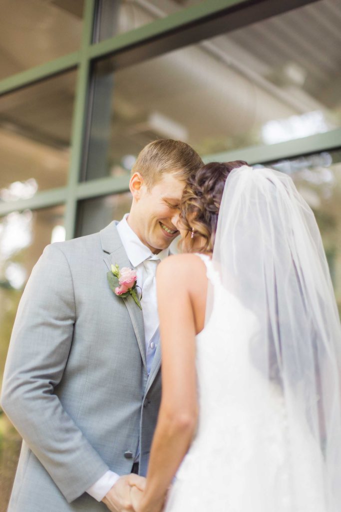 A candid groom and bride kissing during their wedding preparation.