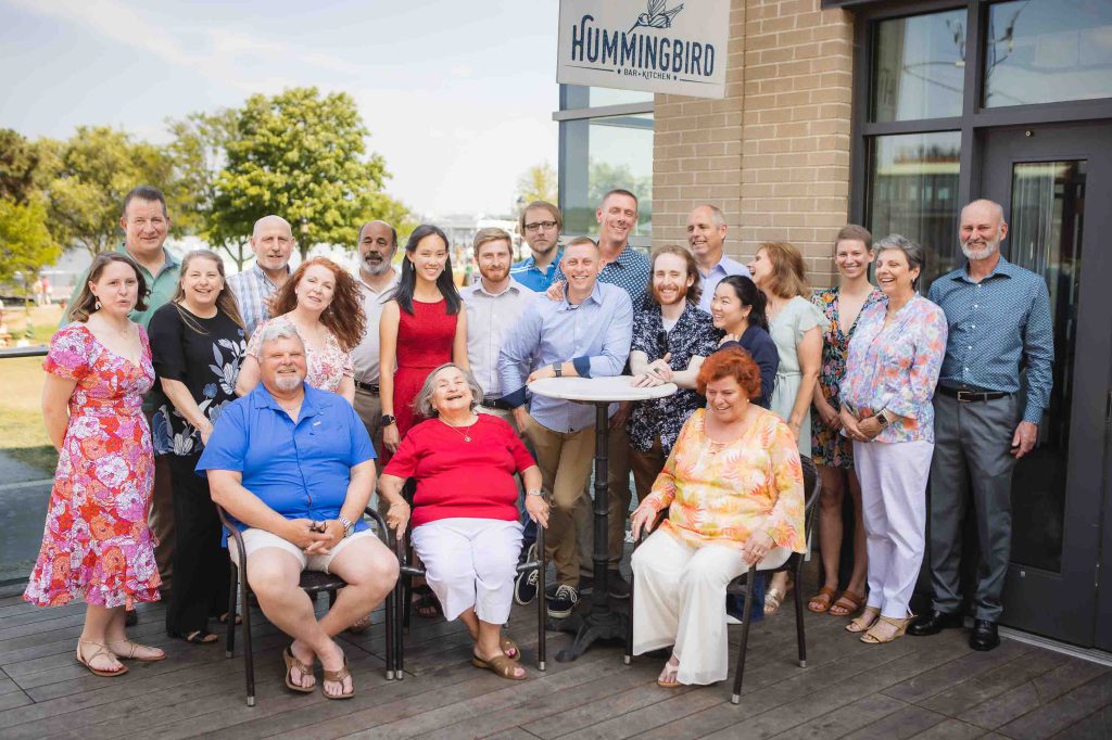 A group of people celebrating a birthday in front of a building.