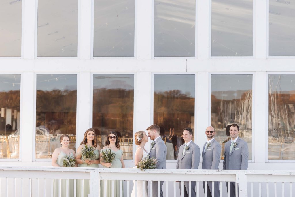 A group of bridesmaids and groomsmen posing for a wedding portrait on the balcony of a building.