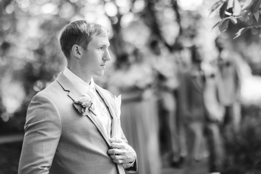 A black and white portrait of a groom at a wedding.
