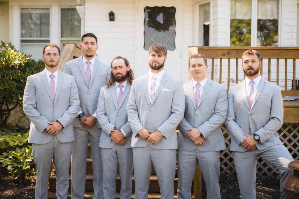 A group of groomsmen in grey suits posing for a wedding portrait.
