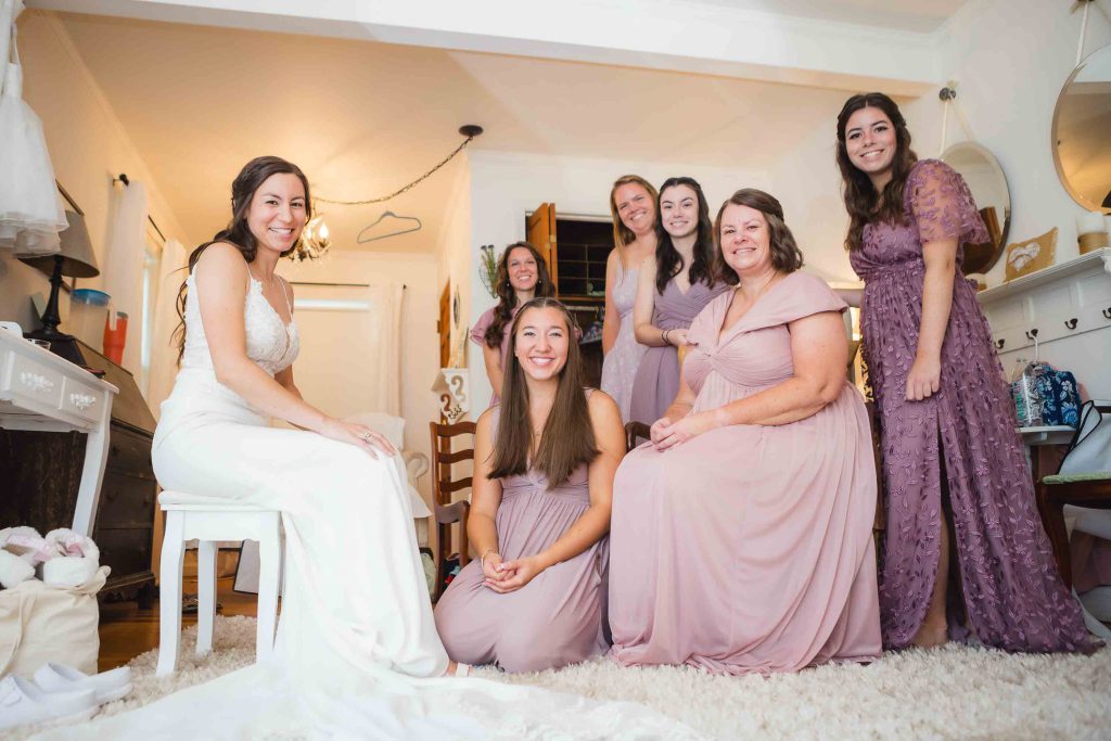 The bride and her bridesmaids candidly pose for a wedding photo.