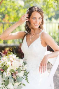 A bridal portrait of a bride in a white dress sitting on a chair.