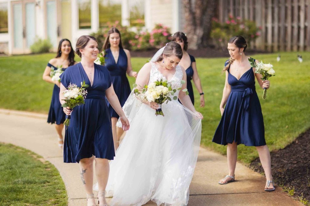 A wedding portrait of a bride and her bridesmaids walking down a path.