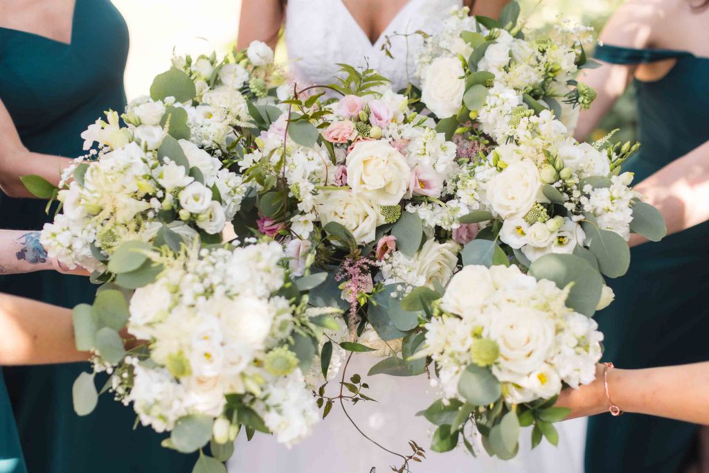 Details of a wedding ceremony with a bride and her bridesmaids holding bouquets.