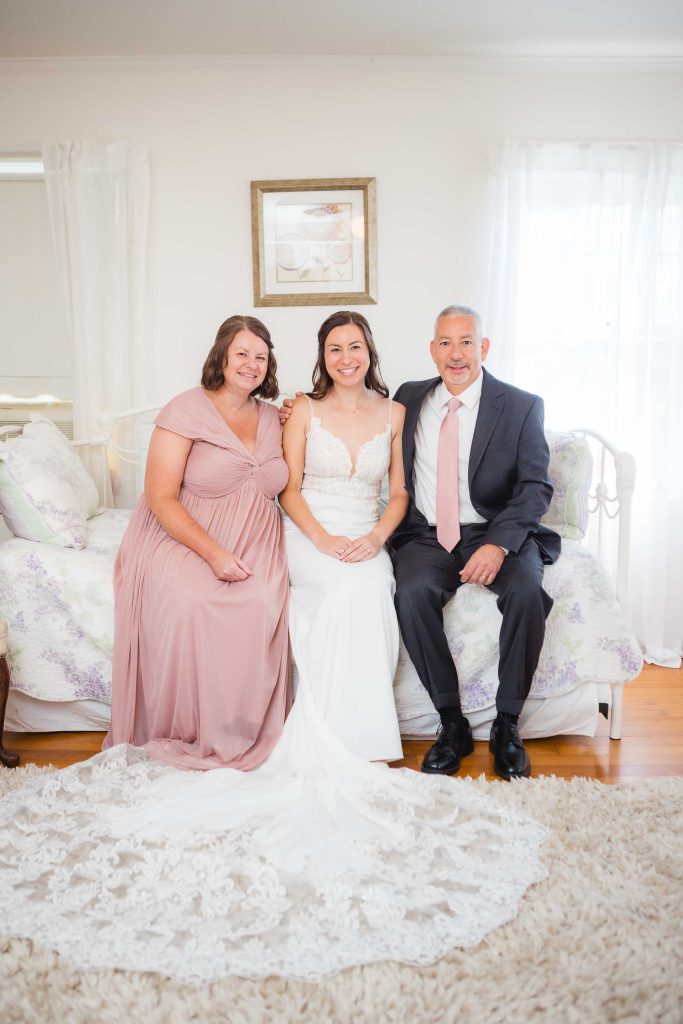 A candid wedding photo captures a bride and her parents during wedding preparation.