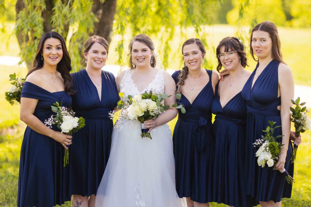 A group of bridesmaids in navy dresses posing for a wedding portrait.