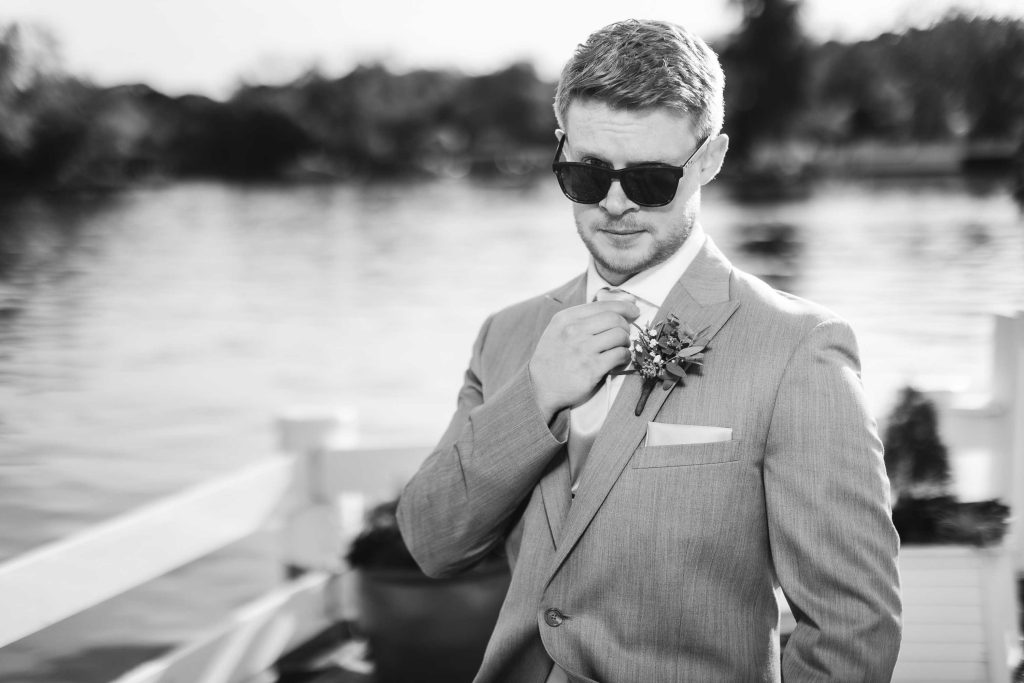 A black and white photo of a man in a suit, sunglasses, and portrait.