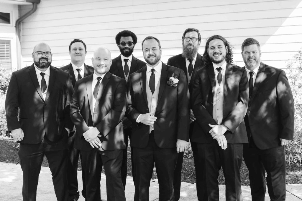 A black and white portrait of a group of groomsmen at a wedding.