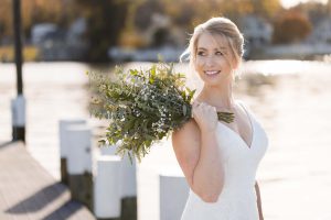 A wedding portrait of a bride holding a bouquet on a dock.