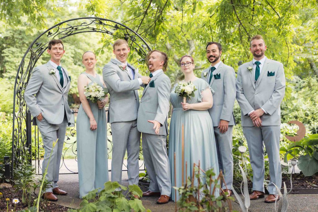 A group of groomsmen posing for a wedding portrait in a garden.