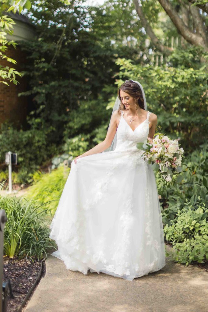 A bride in a white wedding dress posing for a portrait in a garden.